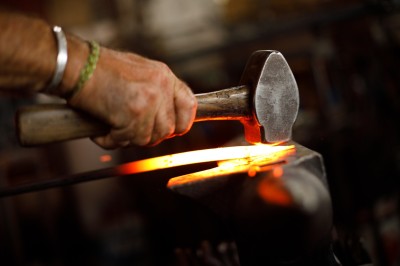 A hammer striking some very hot, glowing metal on an anvil